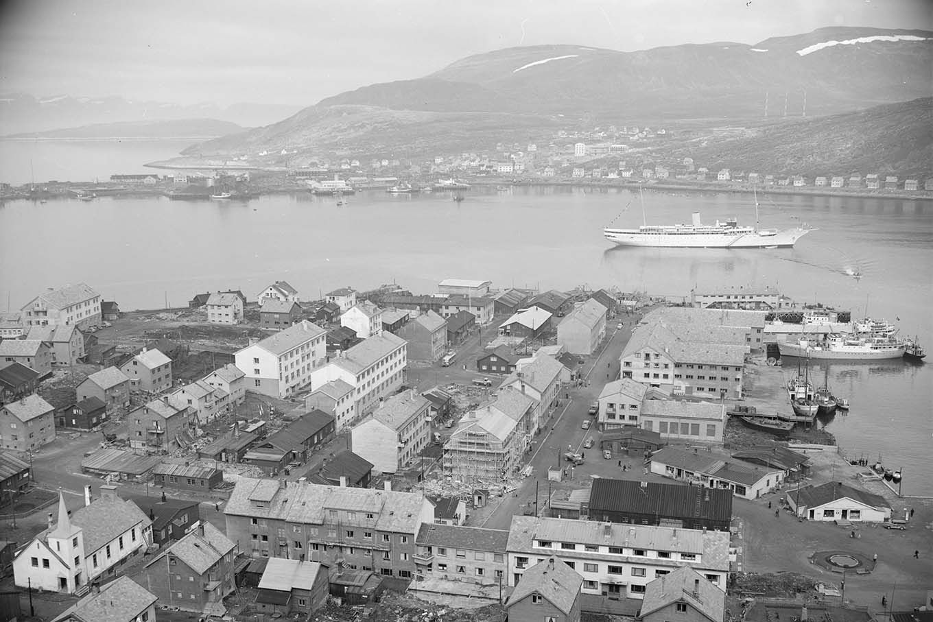 Luftfoto av Hammerfest. Et flott skip, kanskje kongeskipet, ligger i fjorden.