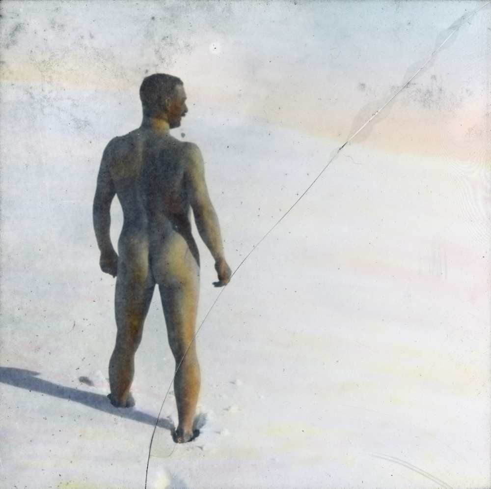 Snebad, 1909. En naken mann står med ryggen til. Håndkolorert dias. 