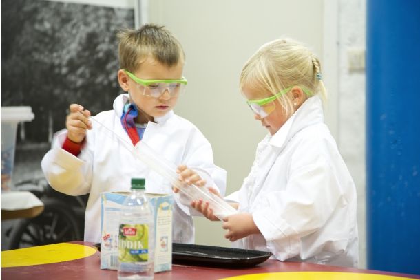 To barn med verneutstyr gjør kjemieksperiment. Foto.