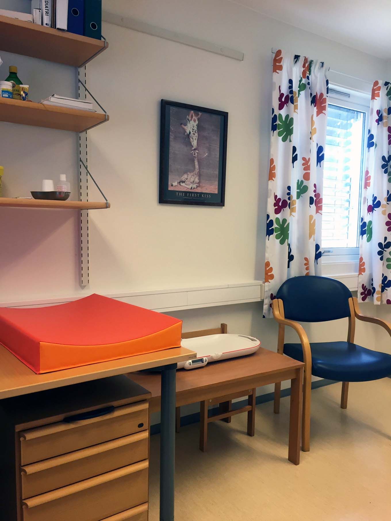 Empty waiting room with changing mat and baby scale. Photo. 