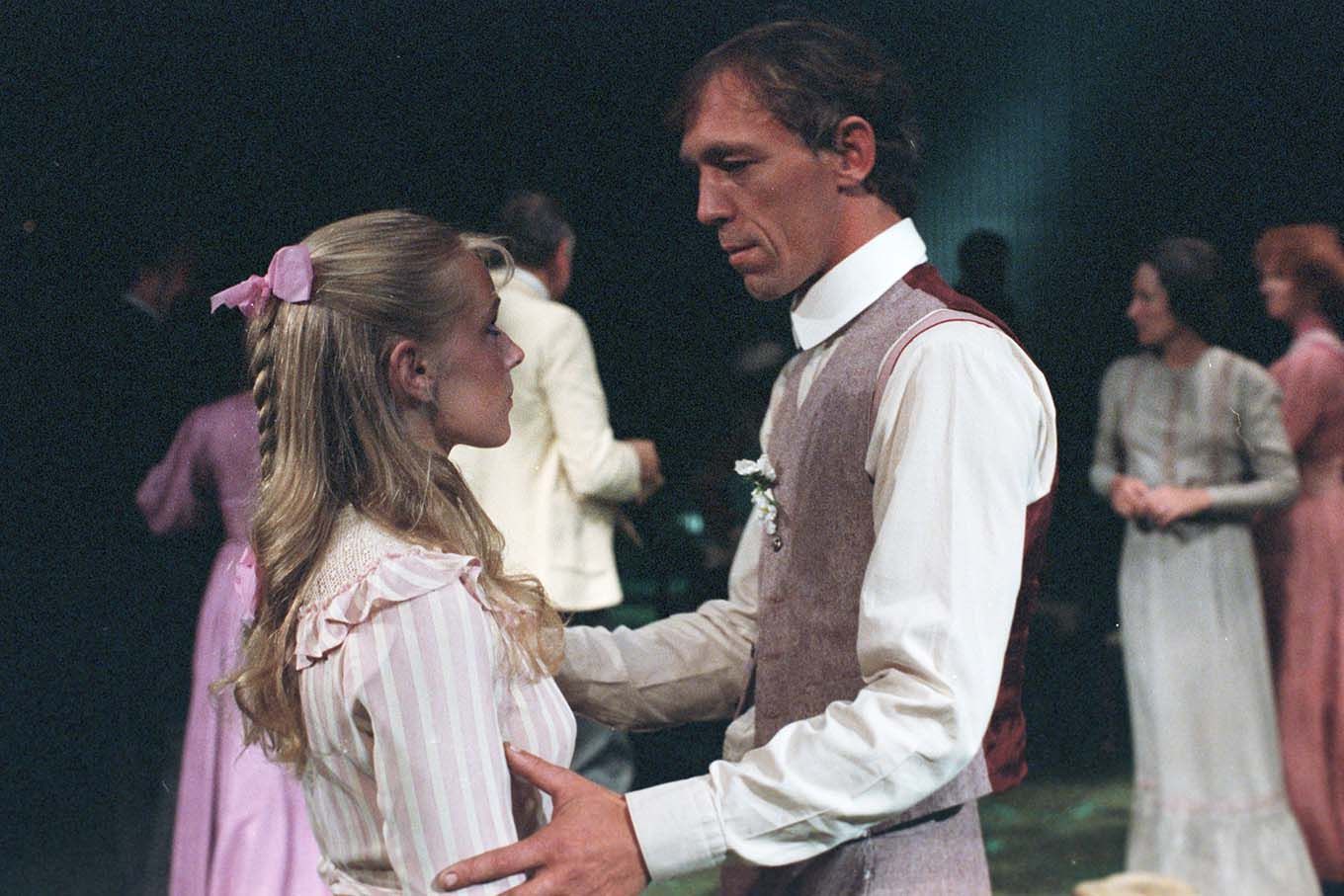 En mann holder rundt armene på en yngre kvinne. Scene fra et teaterstykke. Foto.