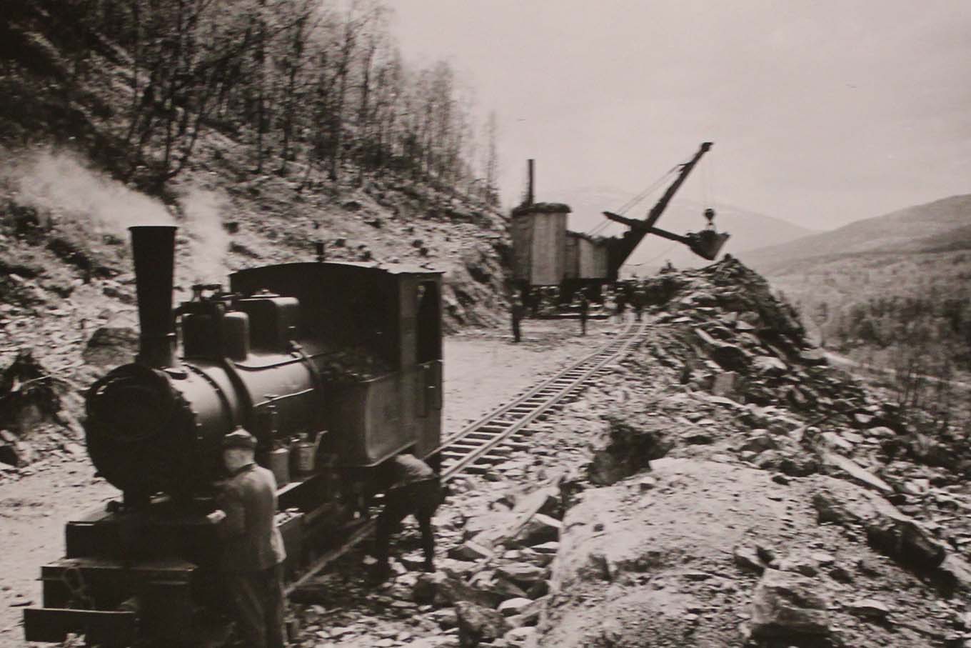 Lokomotiv på jernbanespor ved et anleggsområde. Foto.