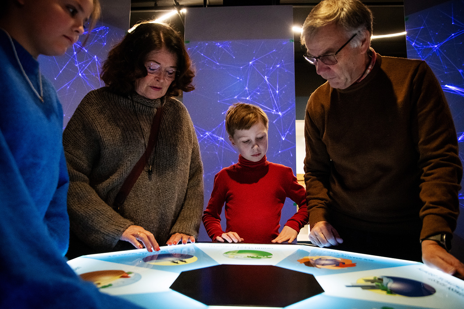 Young girl and boy looking at an exhibition poster with an adult