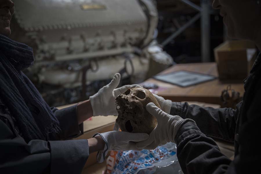 To mennesker står i et lagerlokale og holder en hodeskalle. Foto.