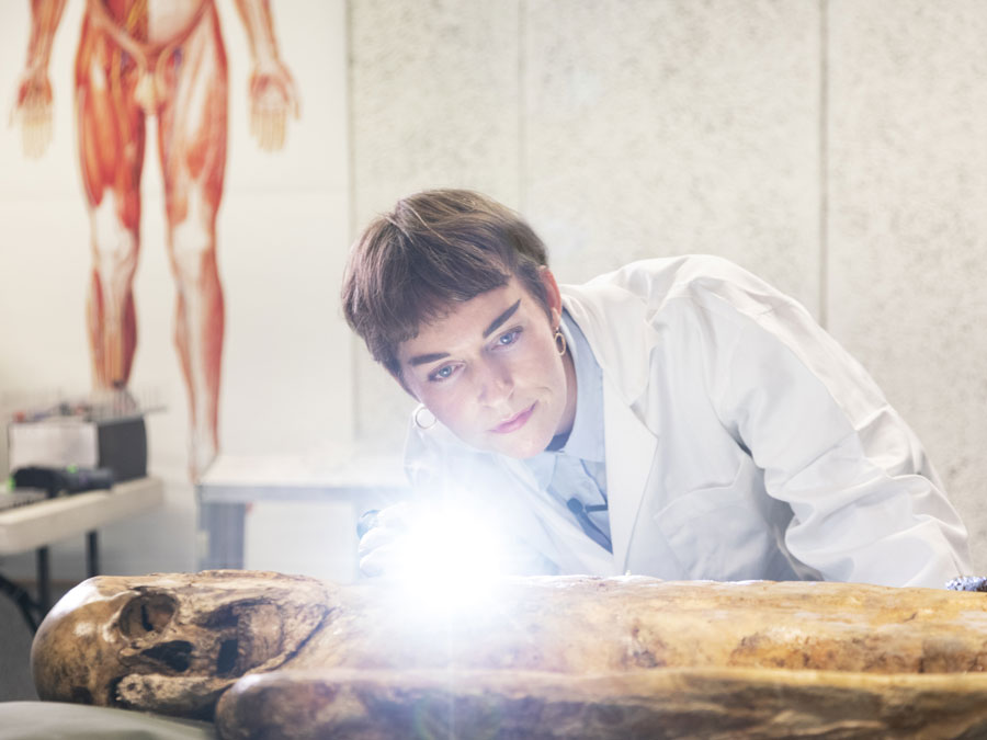 Kvinne med labfrakk studerer et gammelt kolera lik.