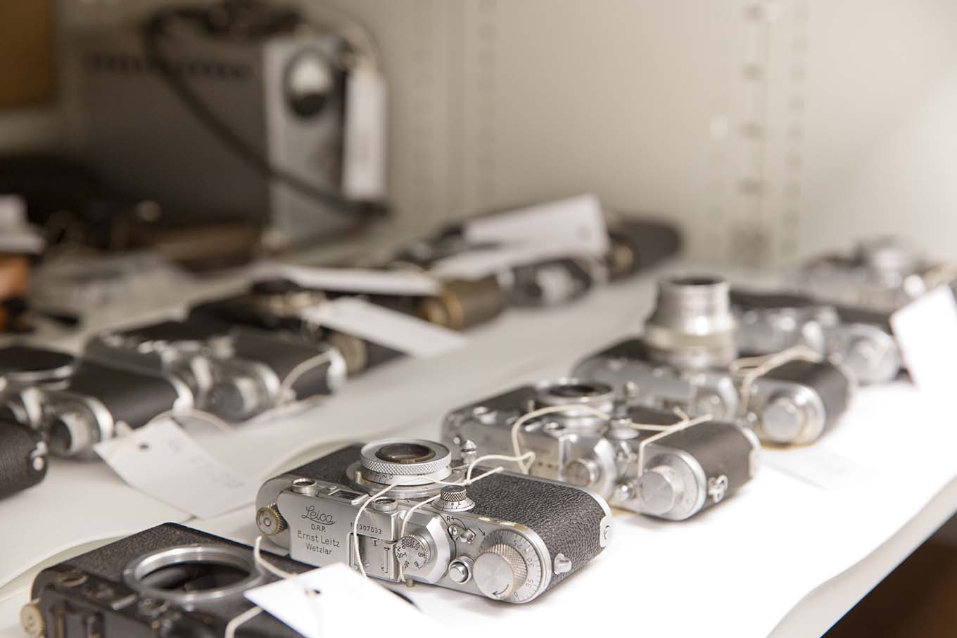 From the camera collections: Compact cameras lined up on a shelf. A Leica camera in focus. Photo: The Norwegian Museum of Science and Technology / Håkon Bergseth.