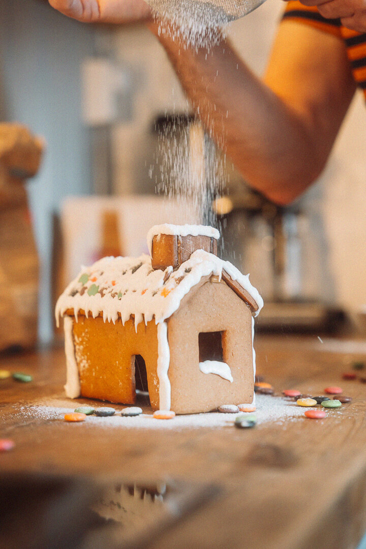 Baker André Løvaas drysser melis over pepperkakehus med nonstop og pynt