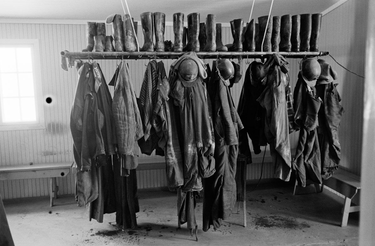 dirty work clothes, boots and helmets hanging on a rack