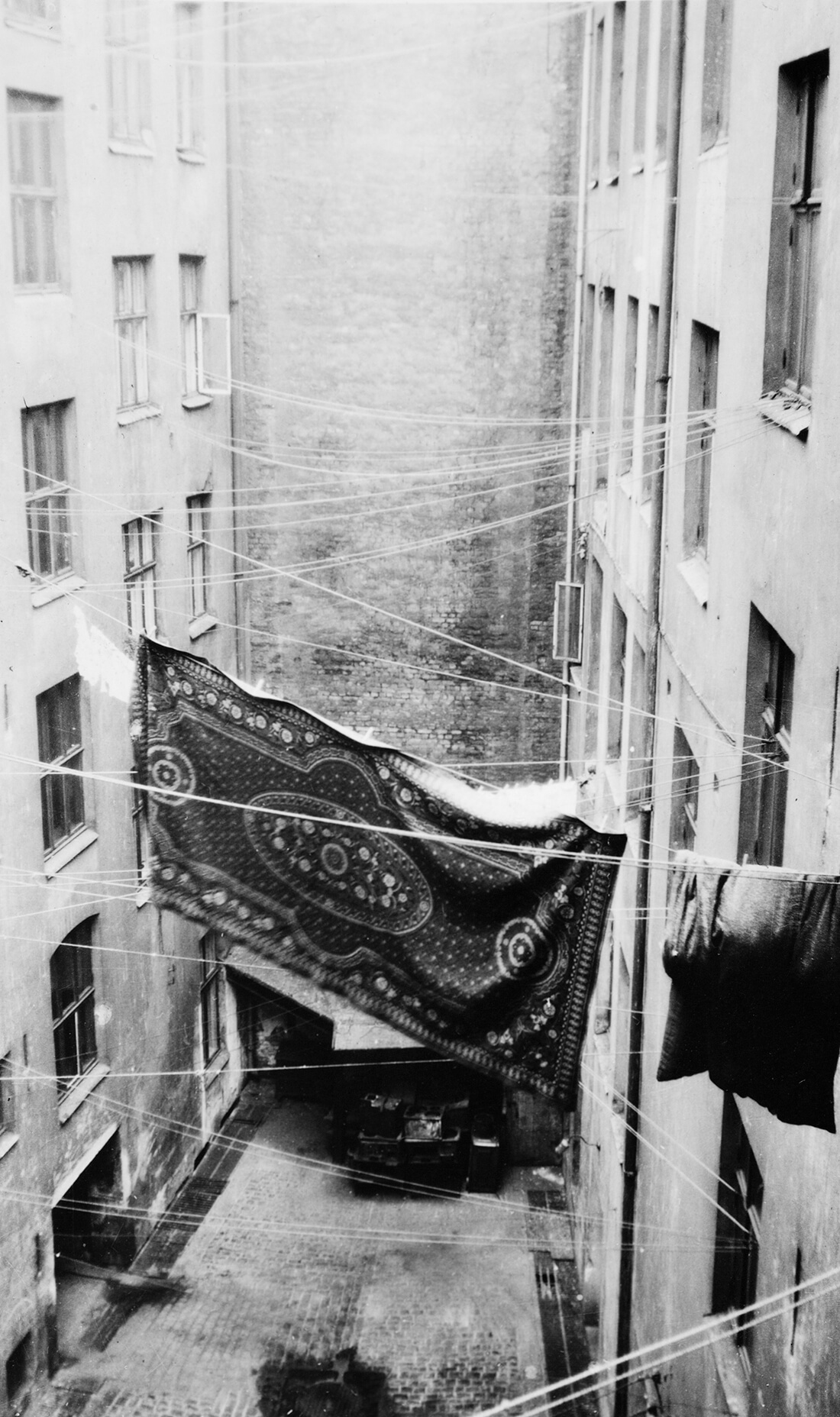 blankets, quilts and textiles hang to dry on clotheslines between buildings