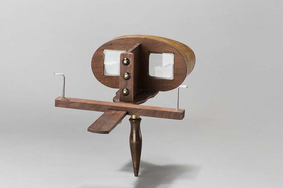 A wooden instrument with two large spectacle lenses.