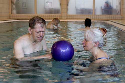 A man and a woman with a blue ball, in a swimming pool. Photo.