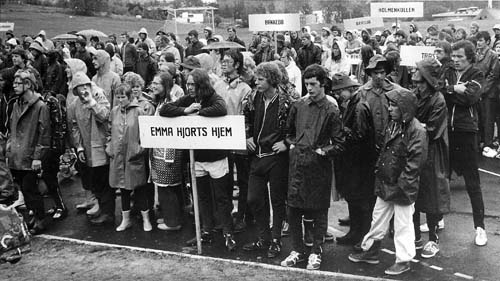 A group of people with a sign marked "Emma Hjort's home", at a sports arena. Photo.