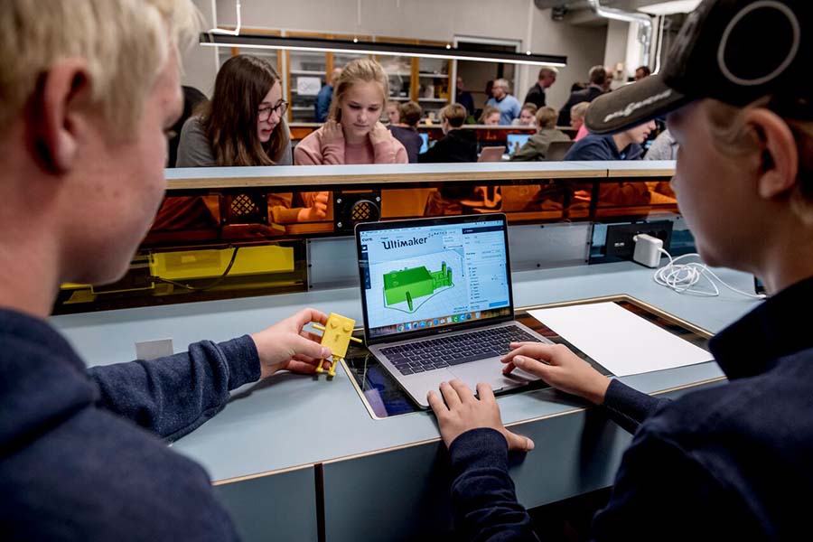 To barn sitter ved en PC og lager 3D-prints. Foto.