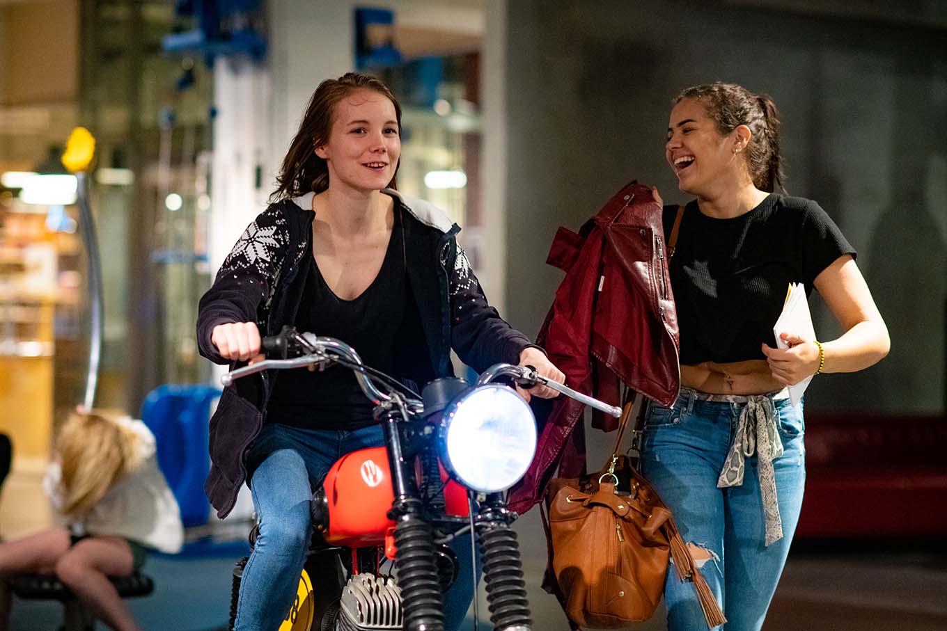 En jente i tenårene sitter på en motorsykkel. Foto.