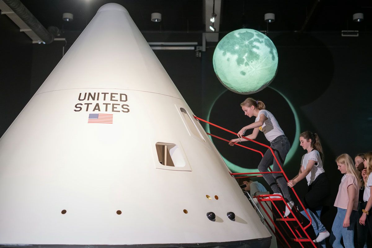 Flere barn står i kø for å klatre inn i en modell av Lunar Lander. Foto