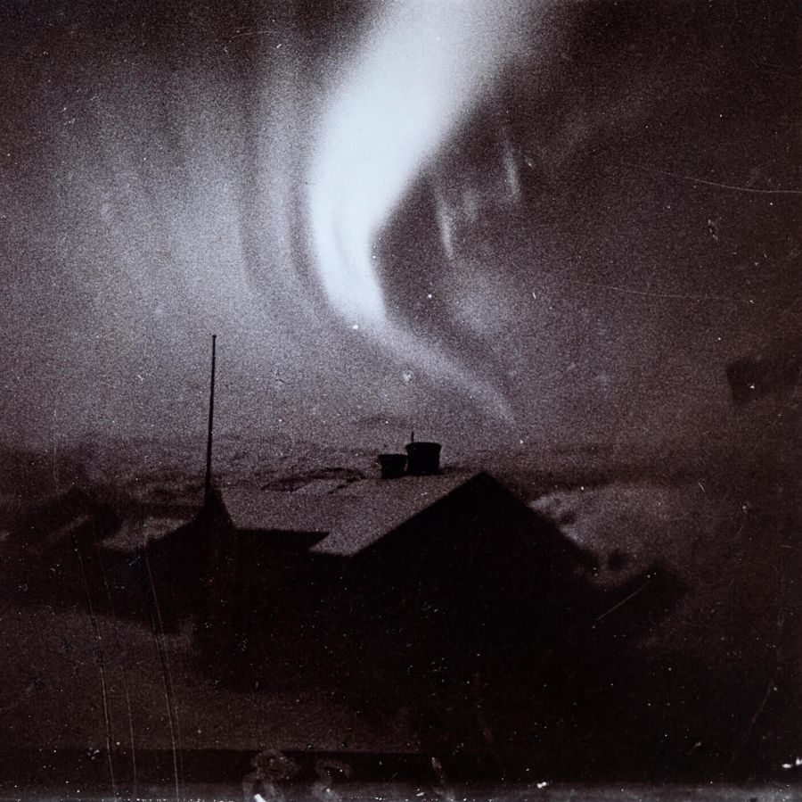 gammelt fotografi av nordlys over bygninger i vinter landskap 