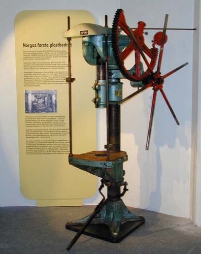 Bakelittpresse med infoplakat i bakgrunnen