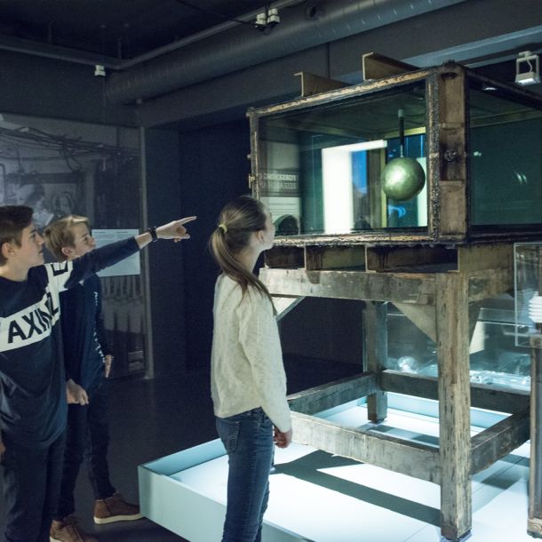3 young people stand around the scientific instrument Terrella. Photo