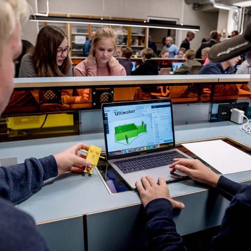 To gutter sitter foran en laptop i et undervisningsrom. Foto