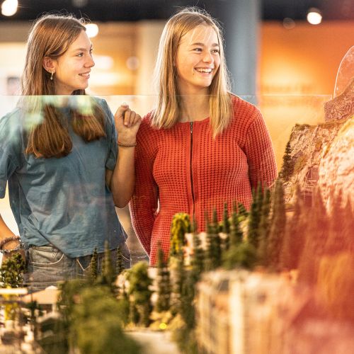 To ungdommer ser på en håndlaget modelljernbane med modelltog på Teknisk museum