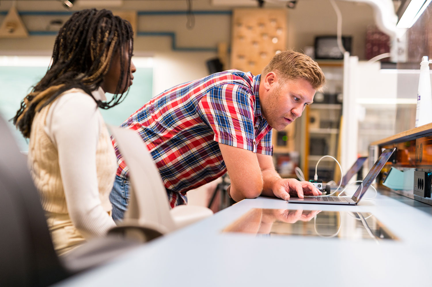 Girl and a science center teacher look at a PC in a teaching room