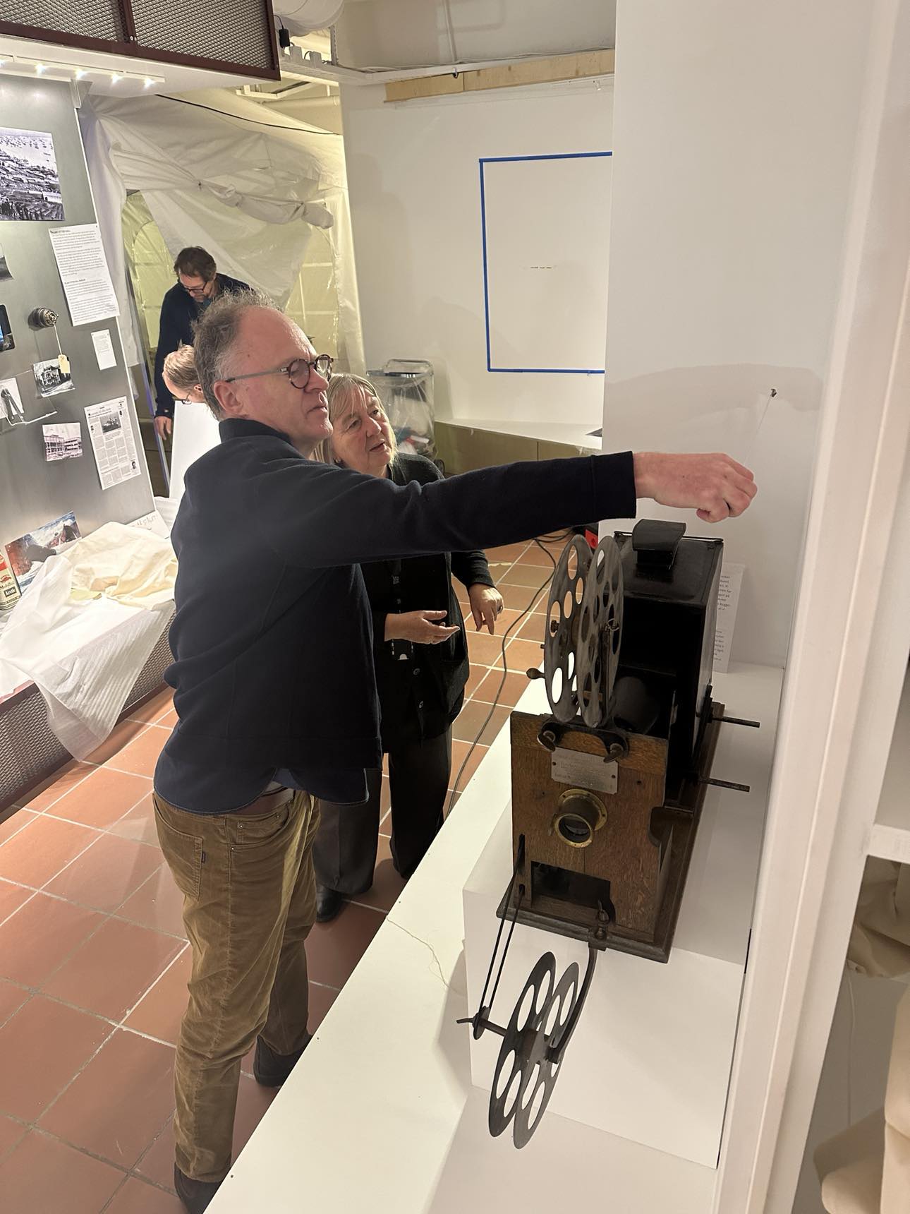 Conservator and photo archivist work with an old film projector in the exhibition
