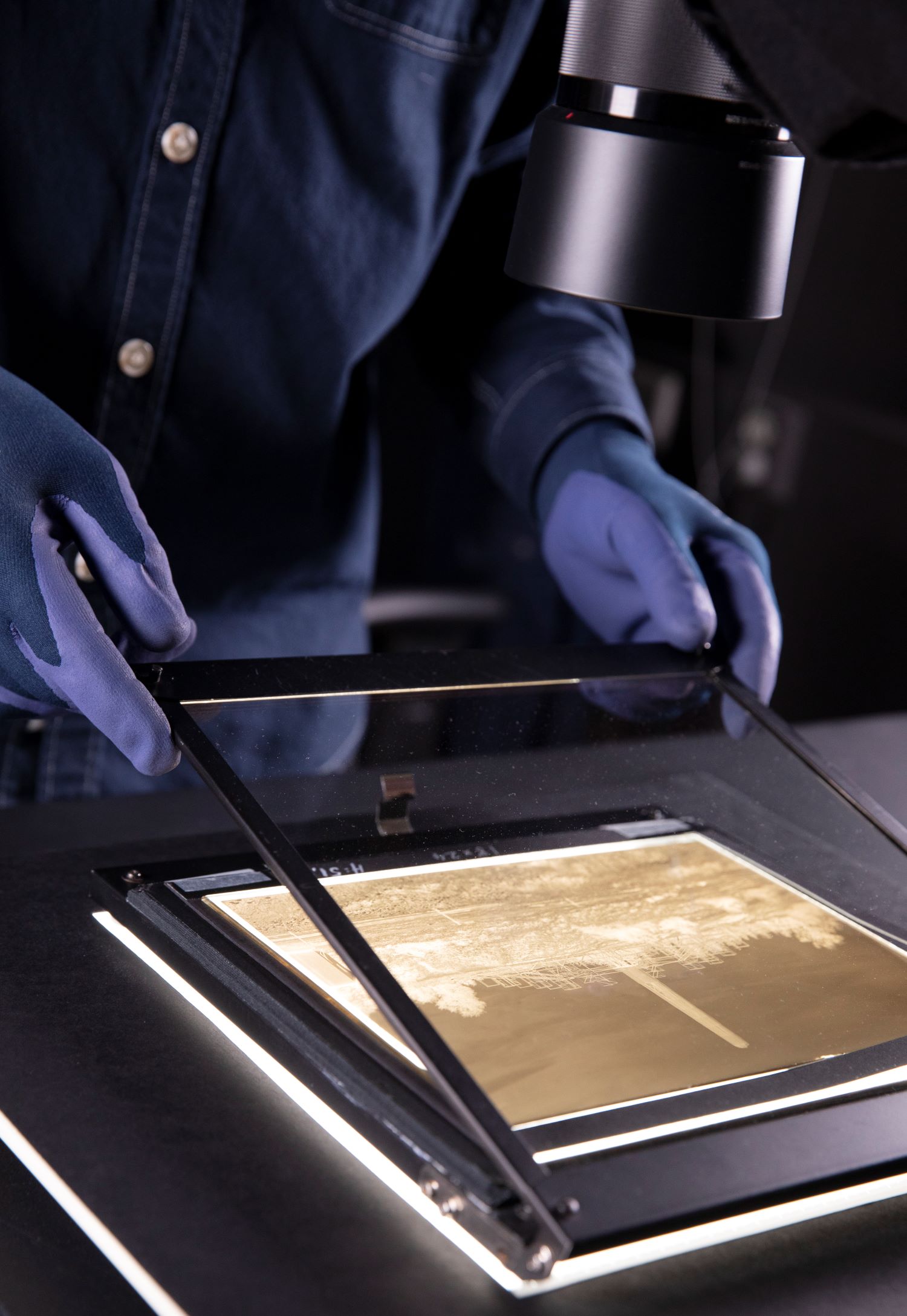 Hands lift up a glass surface on a photograph