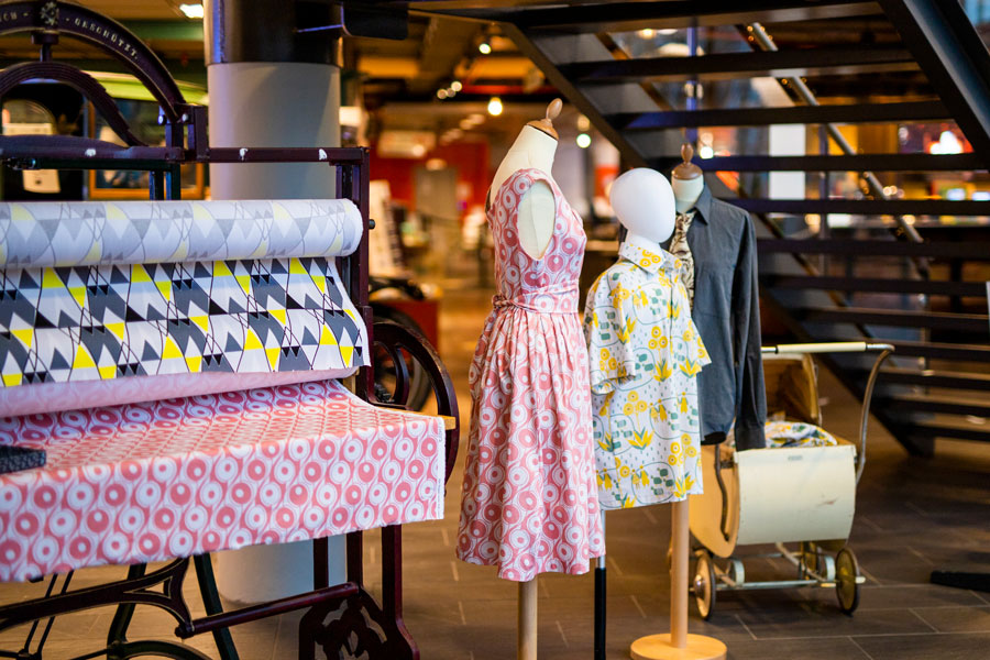 Rolls of fabric and two items of clothing made of the same fabric hung on a mannequin.