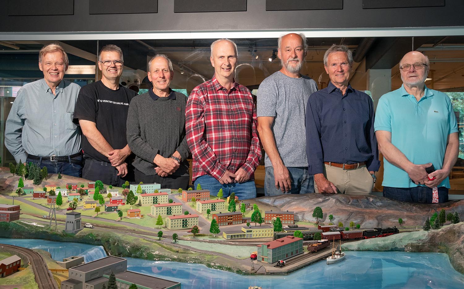 Several elderly gentlemen stand in front of a large model railway