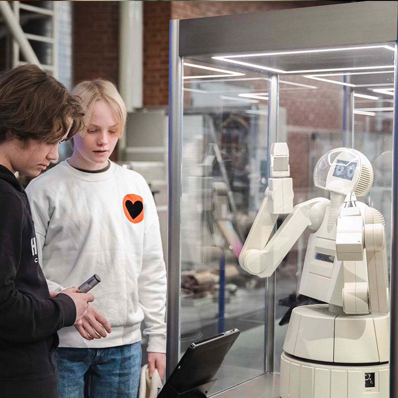 Two young boys looking at a robot in an exhibition