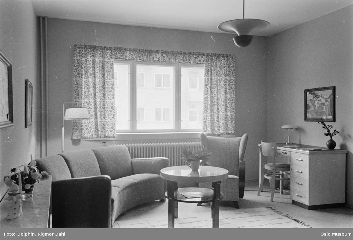 Black and white interior of a living room with window, sofa group and desk