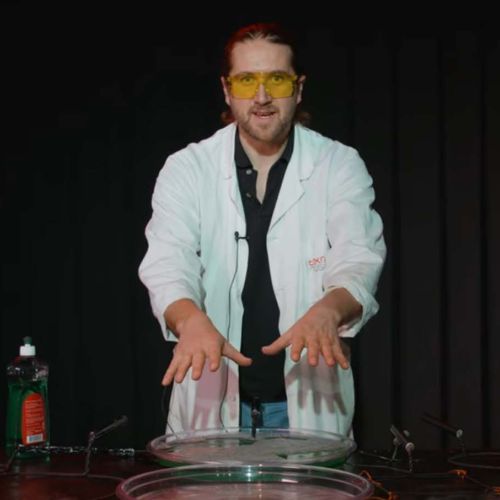 Mann med verneutstyr holder hendene over et fat med såpevann. Foto