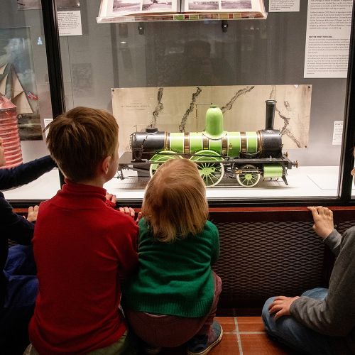 Fire barn som ser på en modell av et lokomotiv i utstillingen