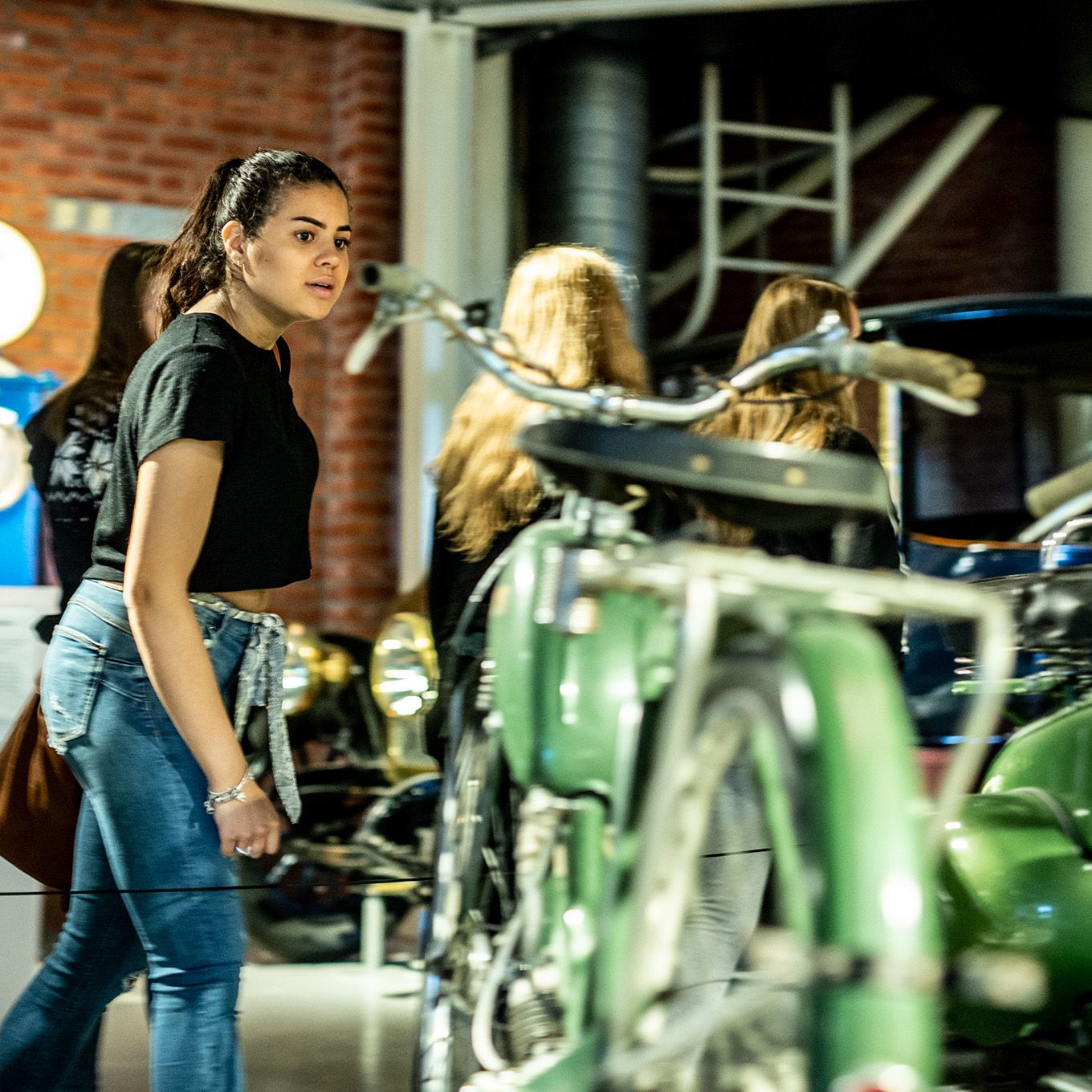 Jente som ser på en grønn motorsykkel på utstilling
